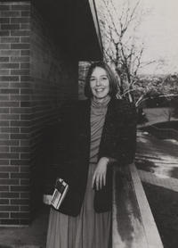 Sandra Woolfrey from her time as director leans on a fence on campus